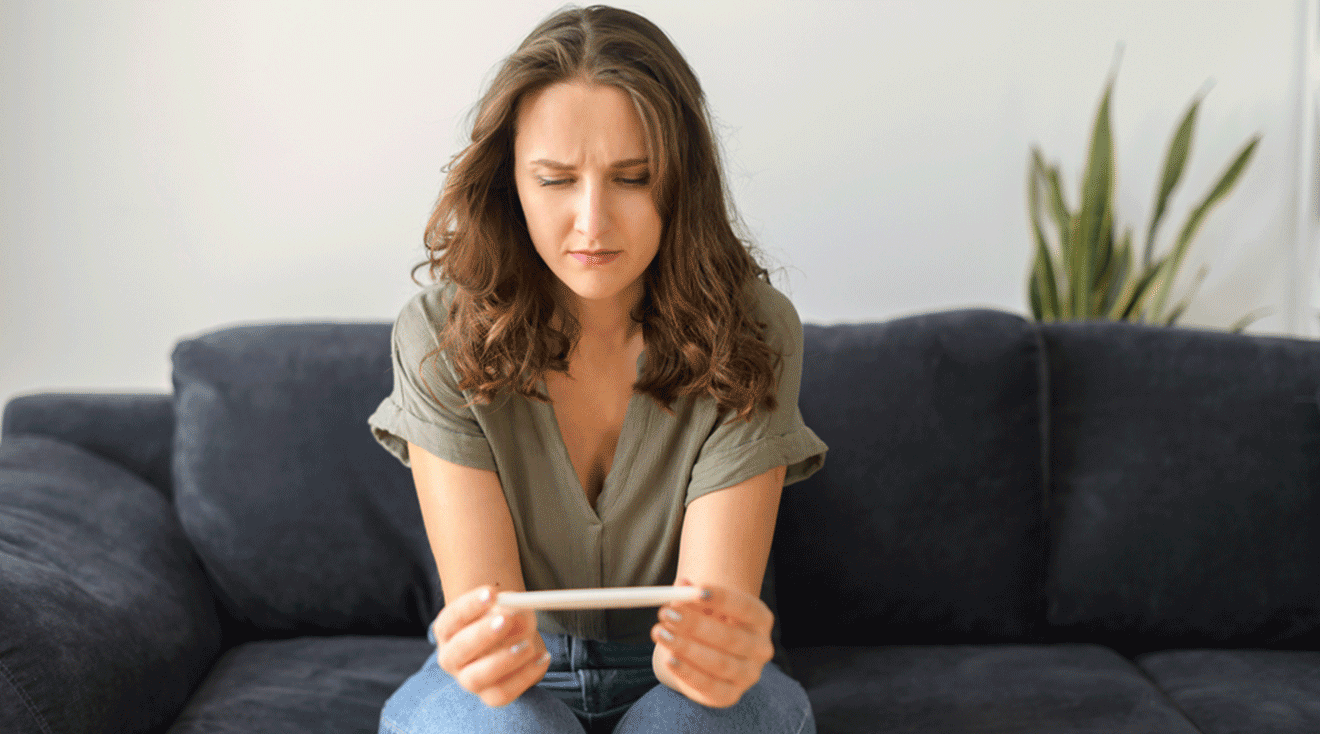 confused woman looking at pregnancy test