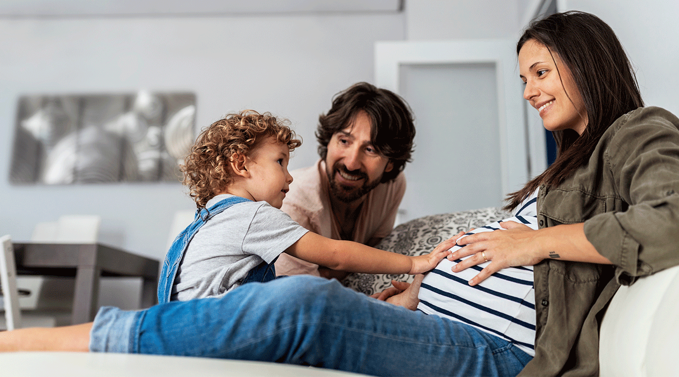 pregnant mom sitting with toddler and partner at home