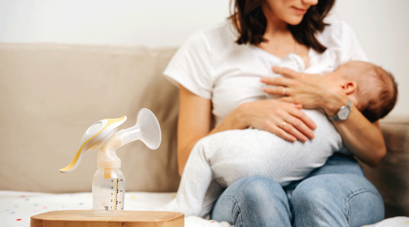 mother breastfeeding baby next to breast pump