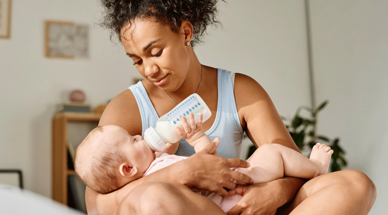 mom giving bottle to baby at home