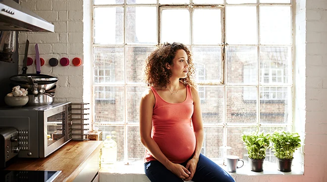 young pregnant woman sitting in kitchen at home