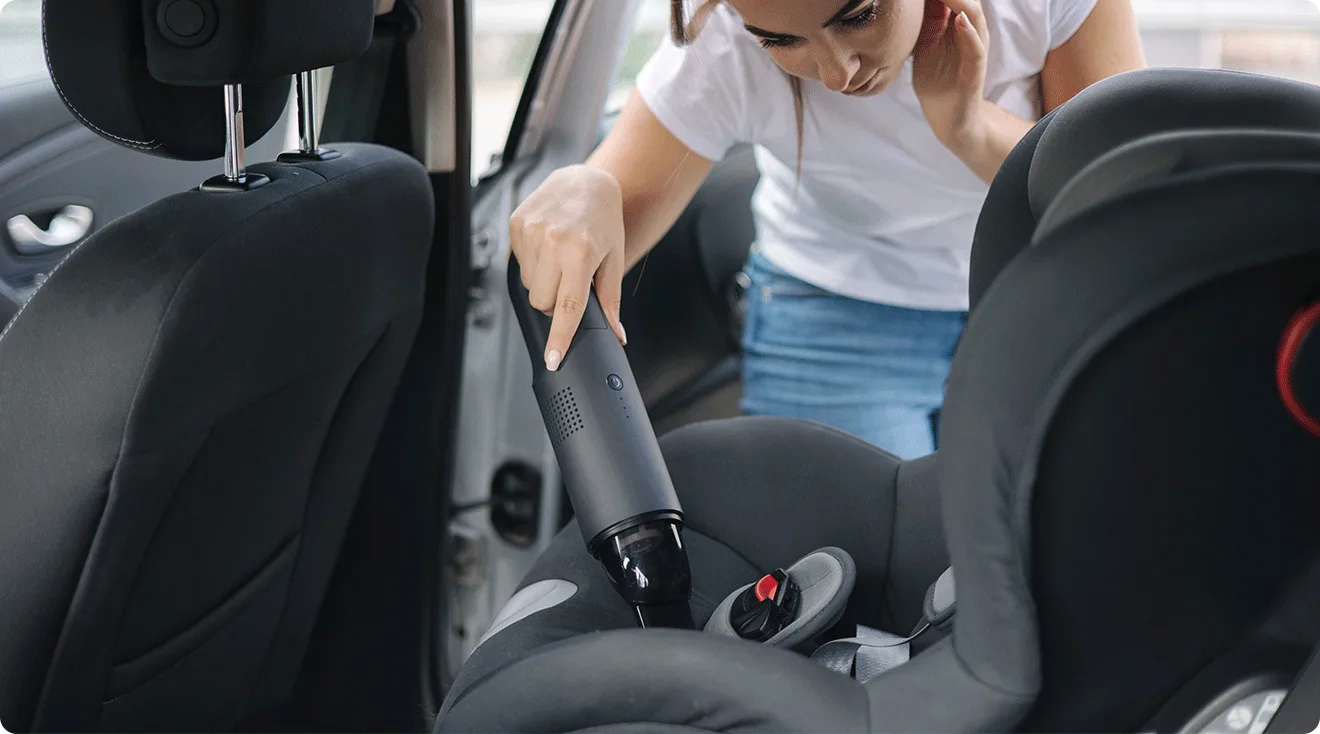 mom cleaning baby car seat with vacuum