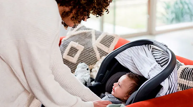 Mom strapping infant son in car seat