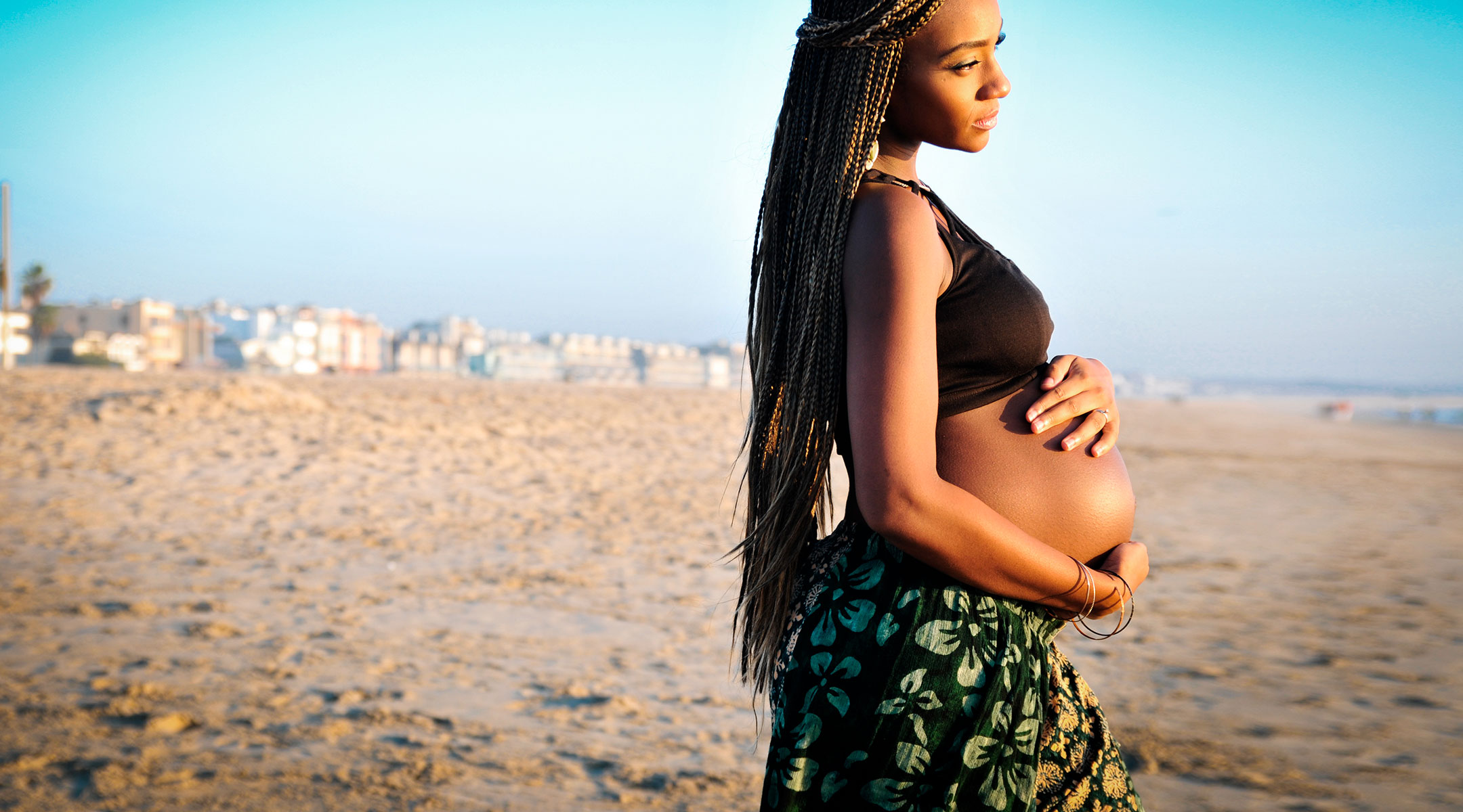 pregnant woman looking at the water on the beach in summer time