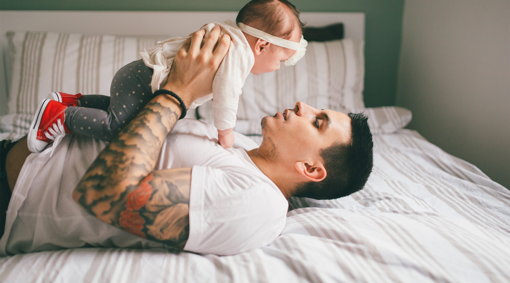 dad holding and bonding with his newborn baby daughter in bed