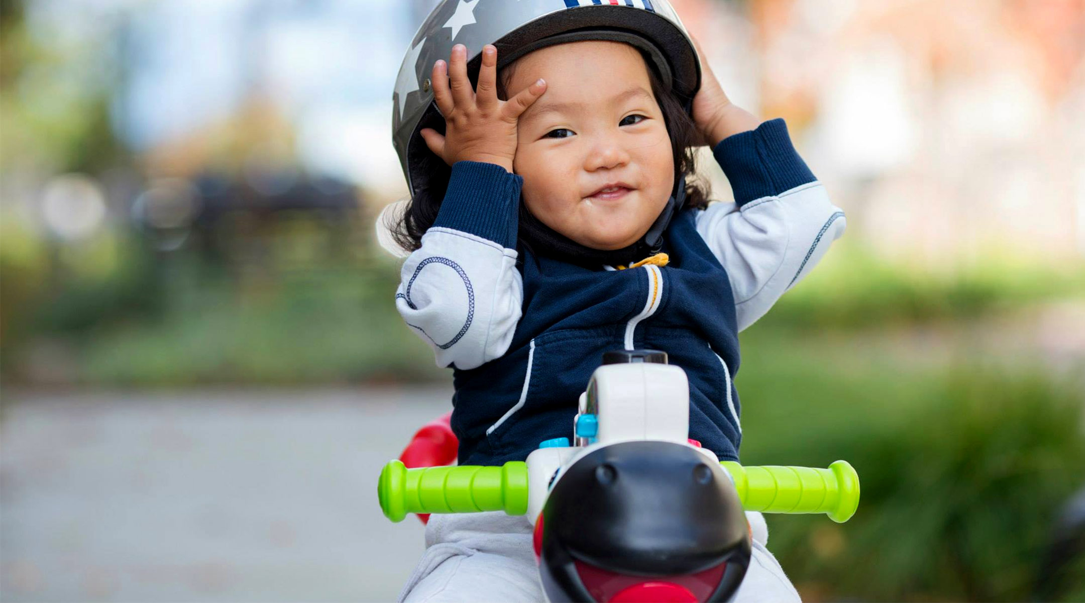 toddler holding helmet on play bike