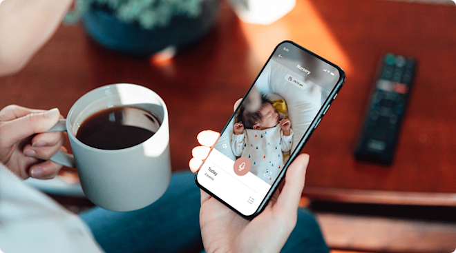 A mom looking at baby monitor on smartphone at home.