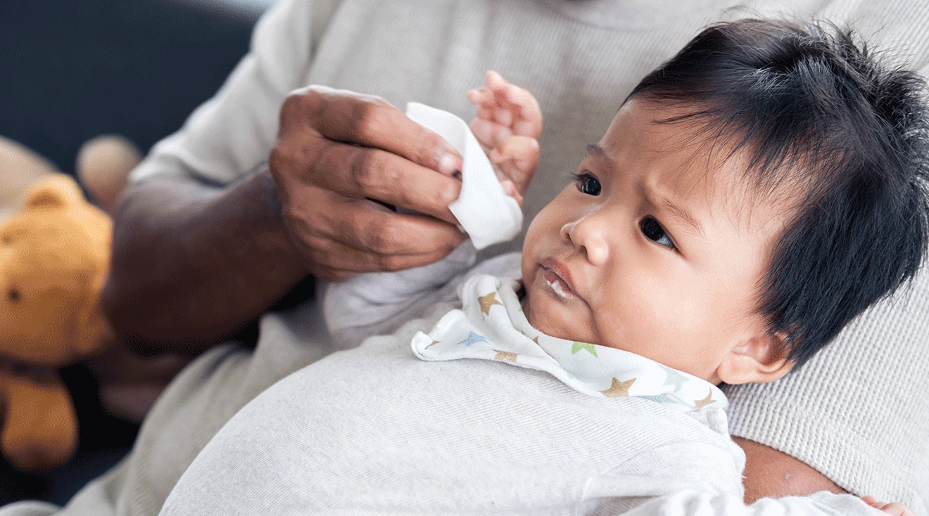 father wiping baby's mouth with cloth