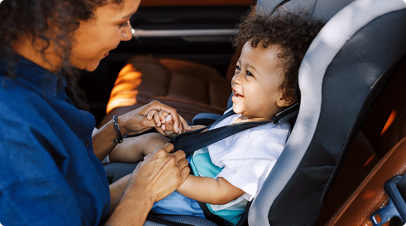mother buckling baby into car seat