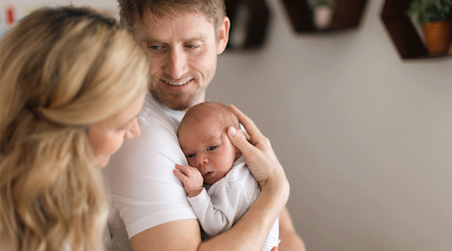dad holding newborn baby at home