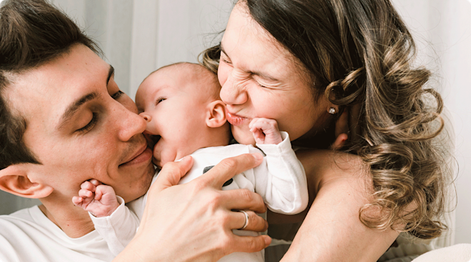 parents kissing and cuddling baby