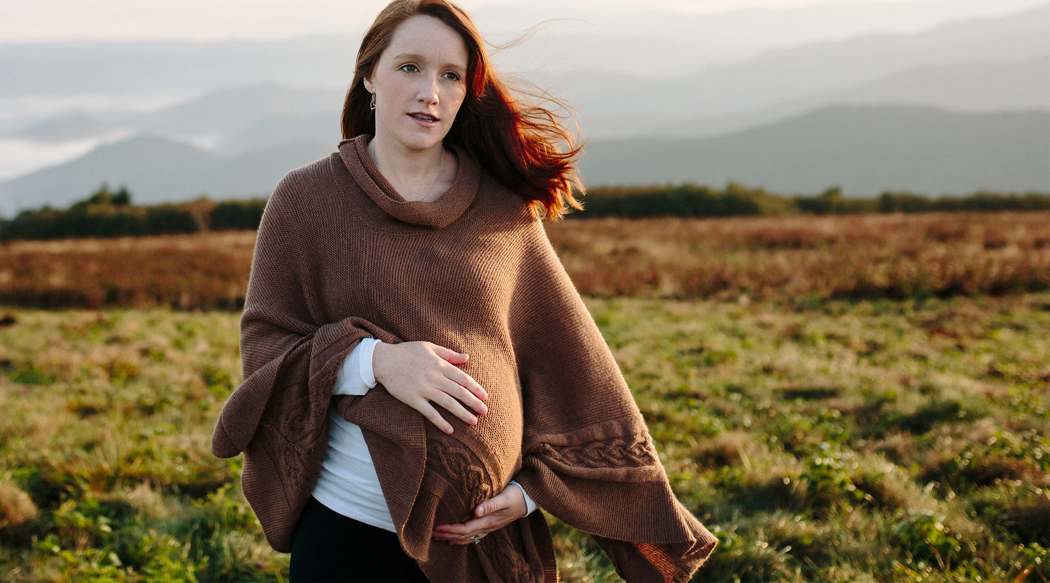 pregnant woman outside near mountains in cold weather