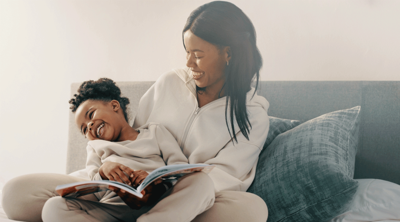 mom and daughter laughing while reading a book