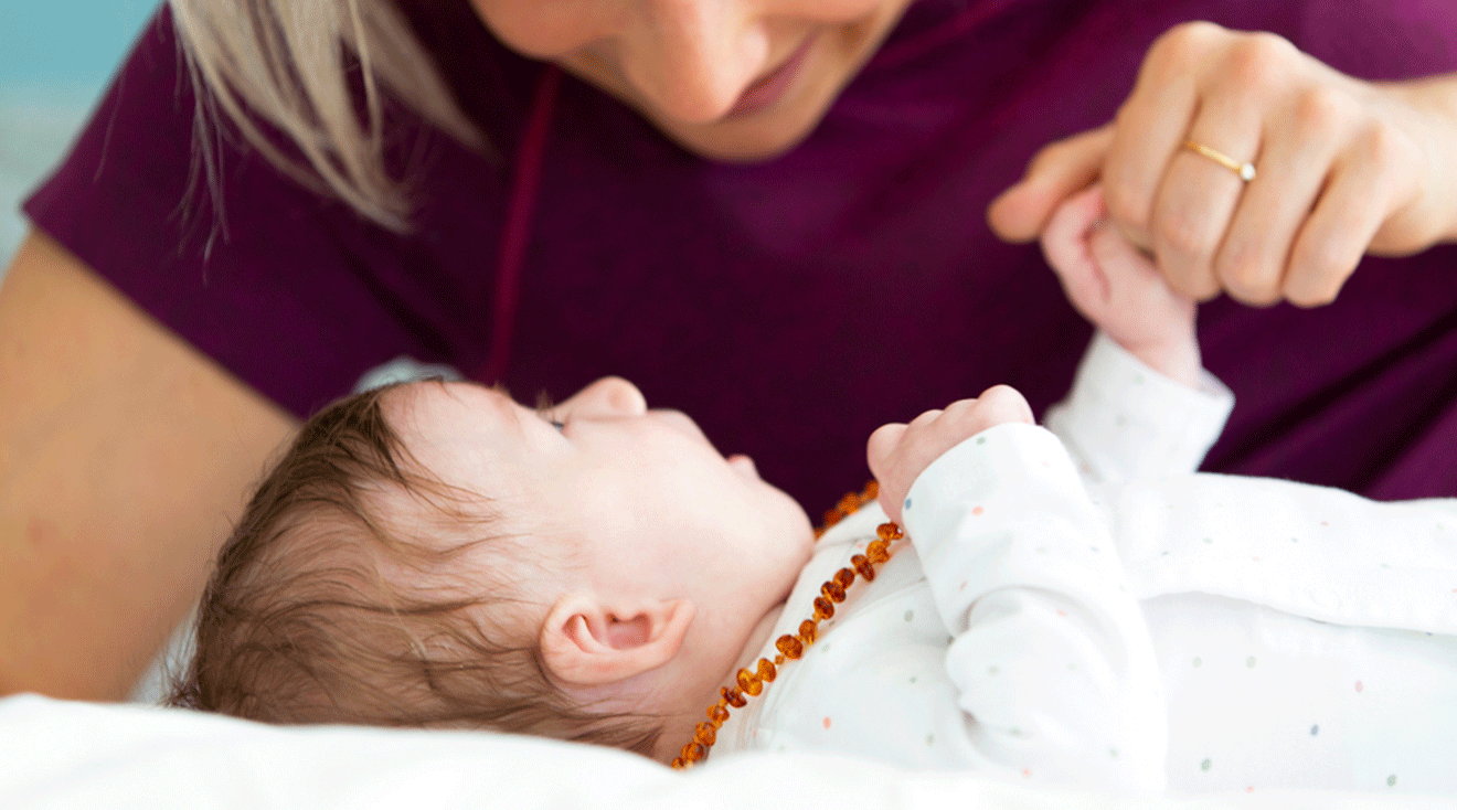 baby wearing an amber teething necklace with mom