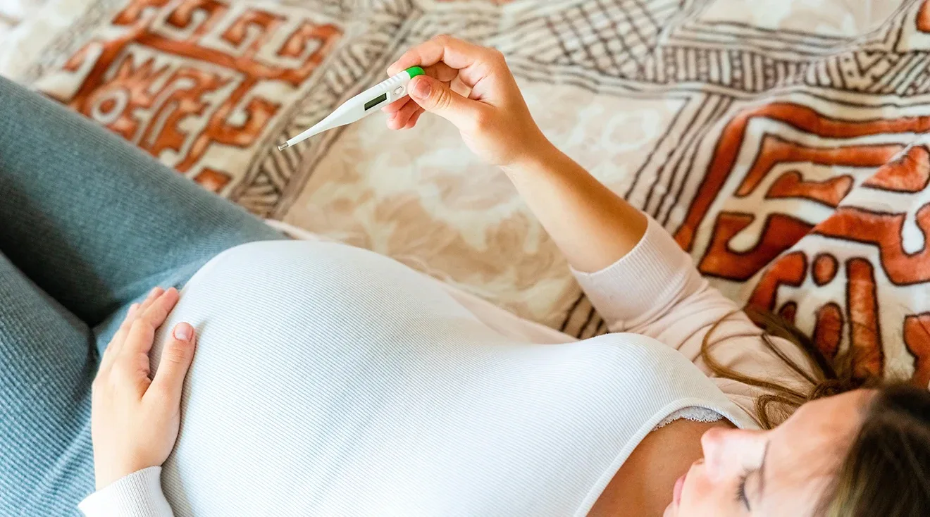pregnant woman taking her temperature