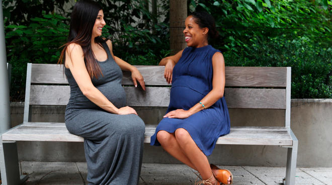 pregnant friends hanging out on a park bench. 