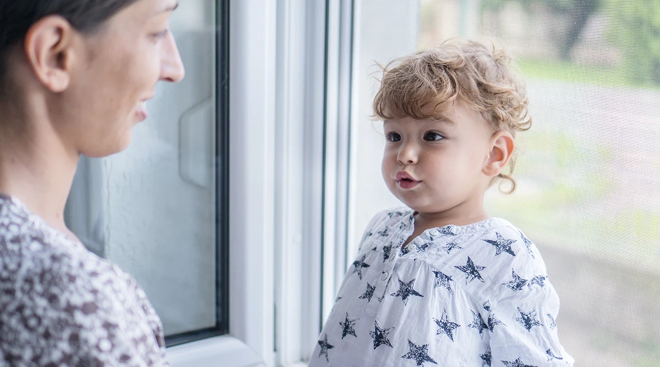 millennial mother talking to toddler at home