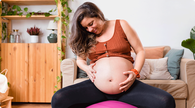 pregnant woman sitting on exercise ball at home