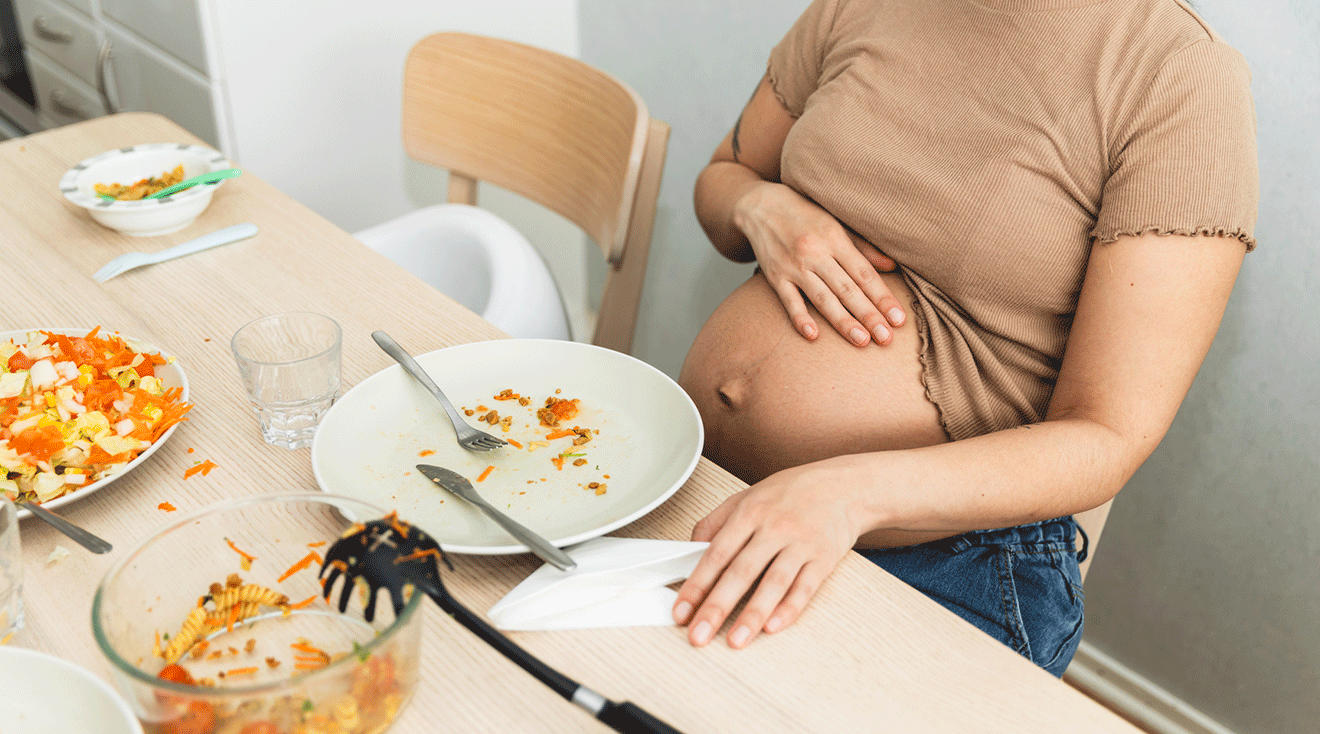 pregnant woman sitting at dining table eating