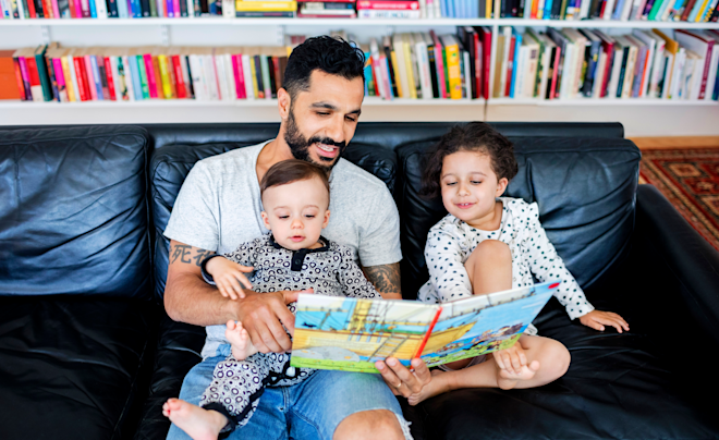dad reading kids' book to kids in living room