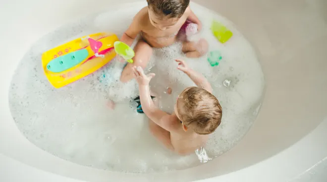 two toddlers in the bath together sharing toys