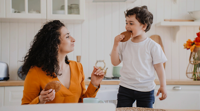 mom sharing a cookie with toddler son at home