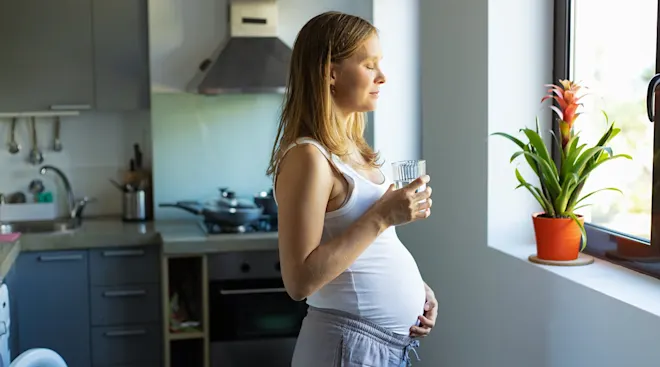 worried pregnant woman standing in kitchen