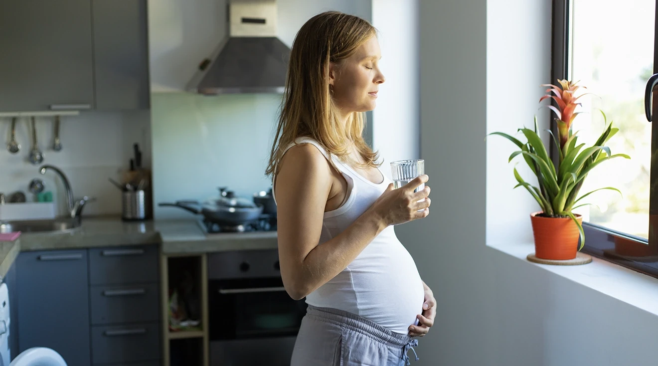 worried pregnant woman standing in kitchen