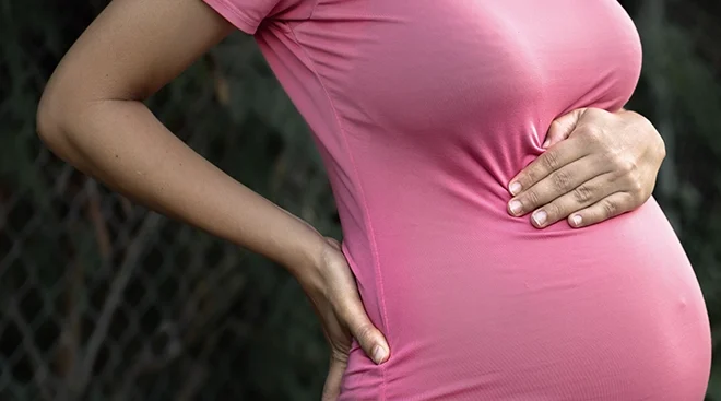 pregnant woman holding belly and back due to pregnancy pains