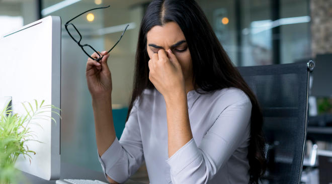 woman touching her eyes while working on computer