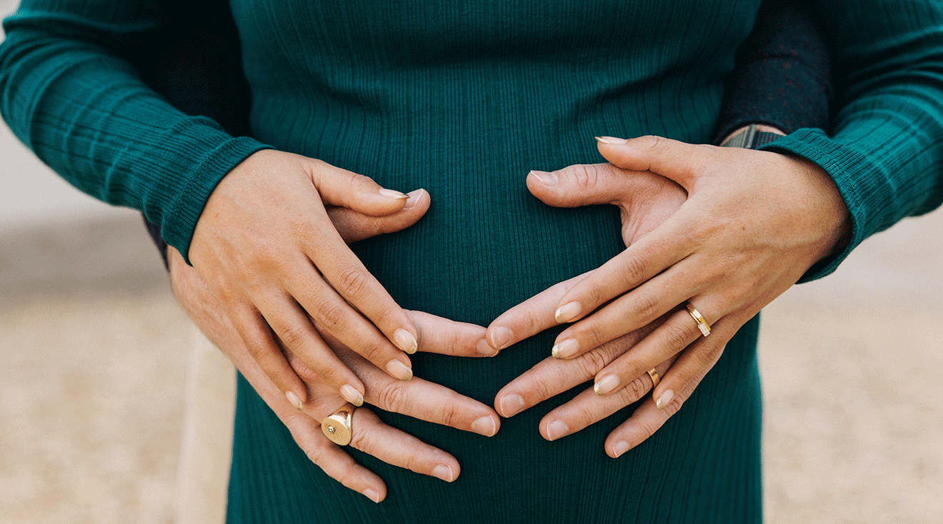 close up of pregnant couple with hands on belly
