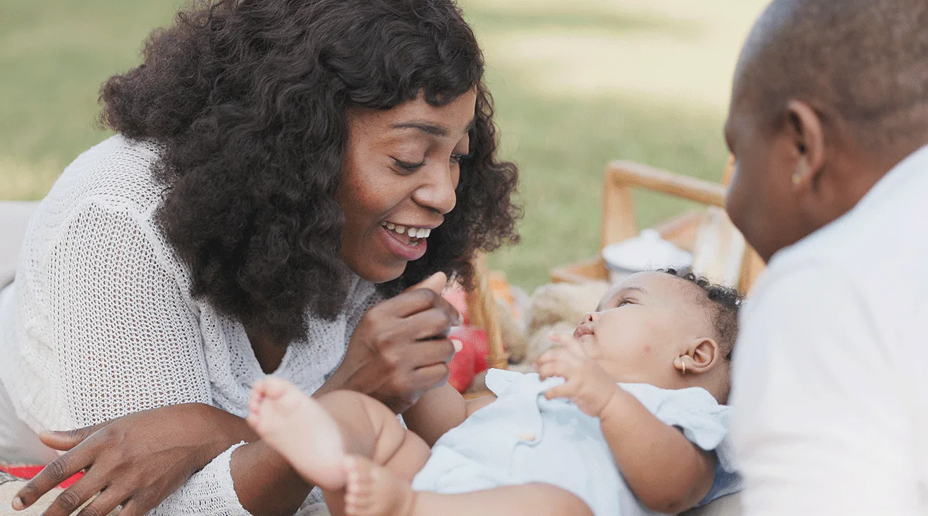 parents playing with newborn baby outside