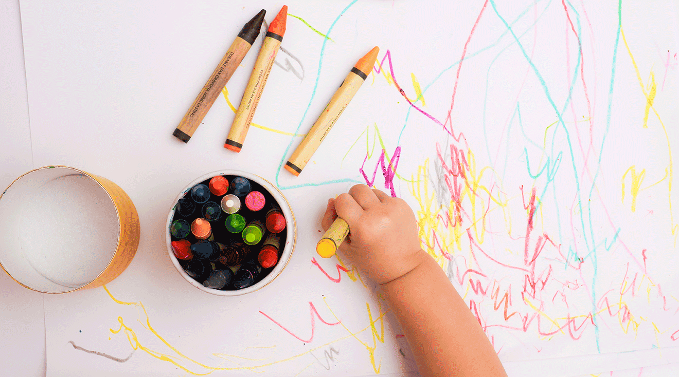 top view of baby drawing with crayons