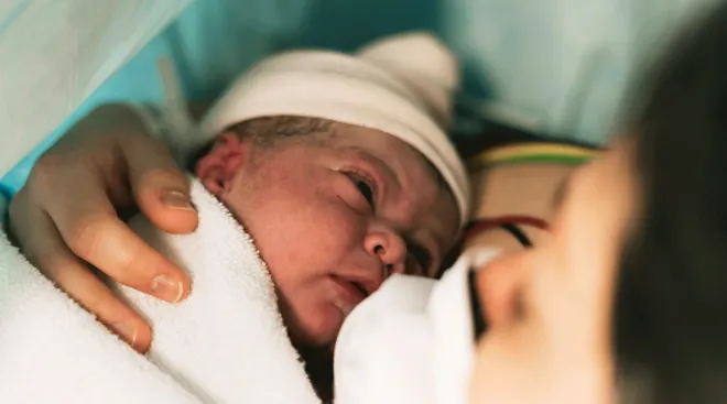 mother holding newborn baby after c section