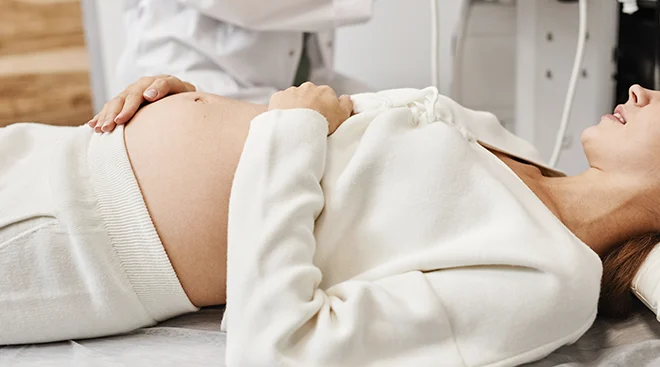 pregnant woman lying on exam table waiting for ultrasound