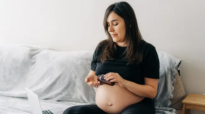 pregnant woman taking medication in bed at home