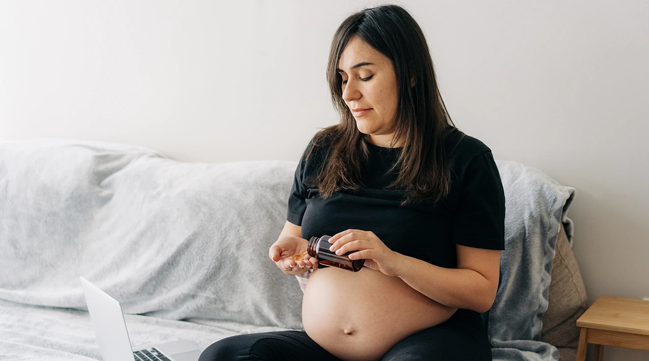 pregnant woman taking medication in bed at home