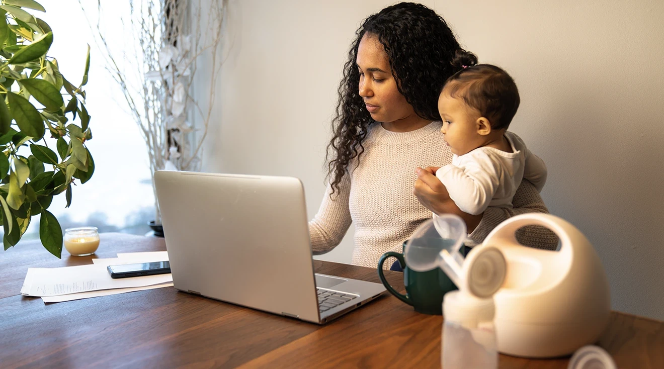 working mother sitting at home with baby and breast pump