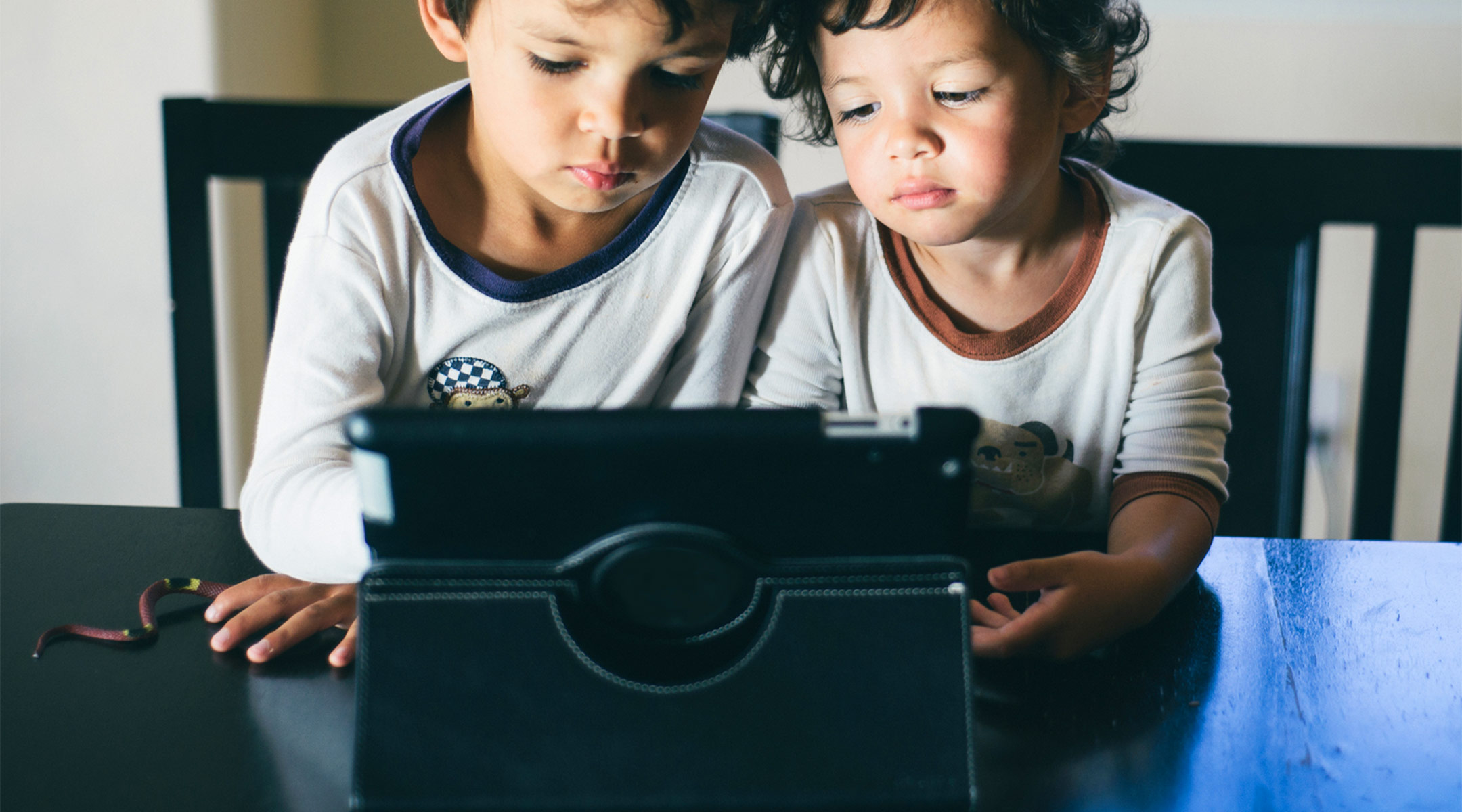two sibling boys watching tablet device