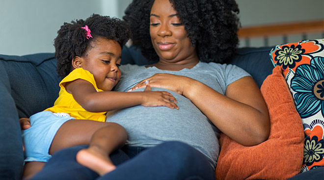 pregnant mom and home with with toddler touching her belly