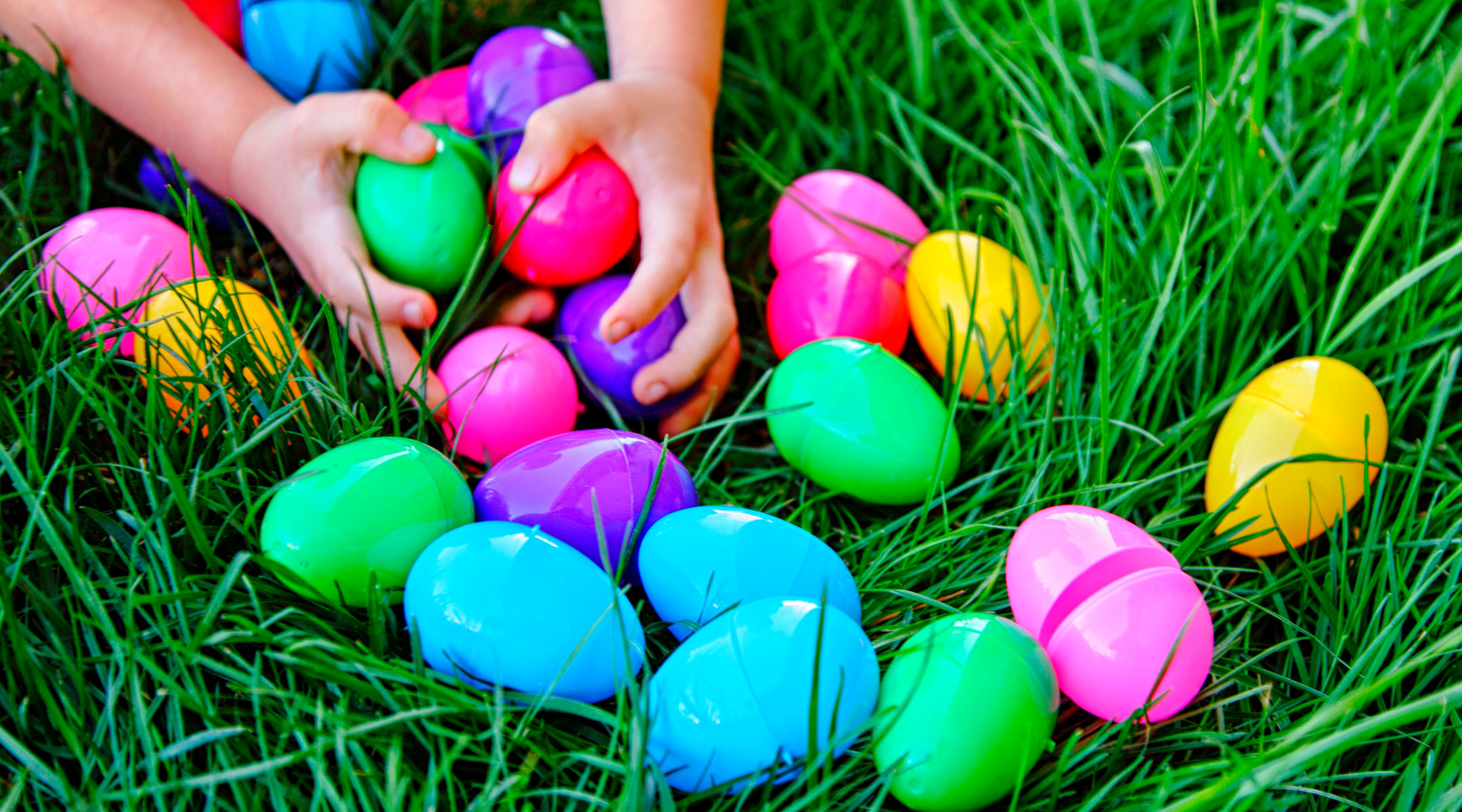 toddler hands grabbing for easter eggs in the grass