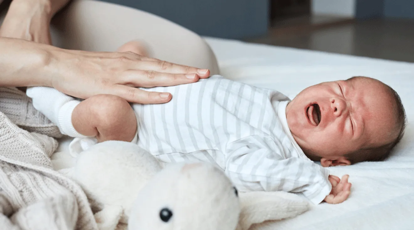 mom's hand on colicky baby's stomach