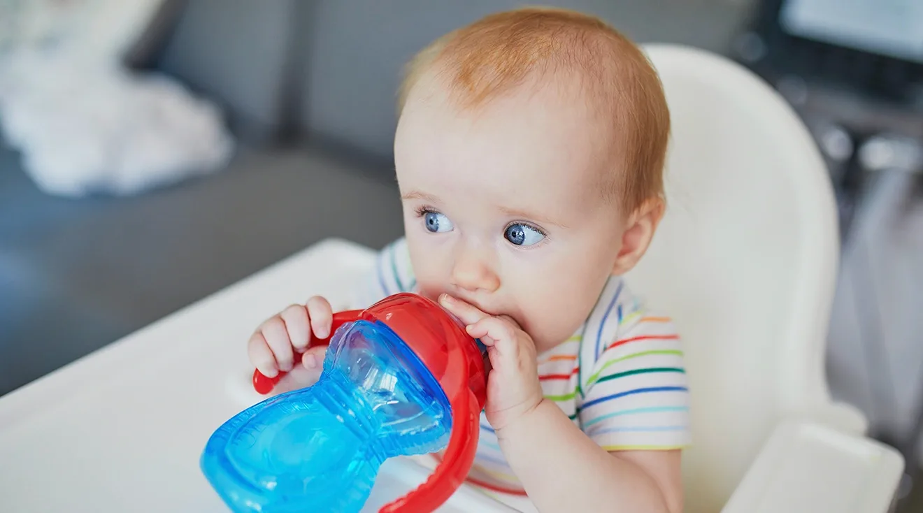 baby sitting in high chair and drinking out of a sippy cup