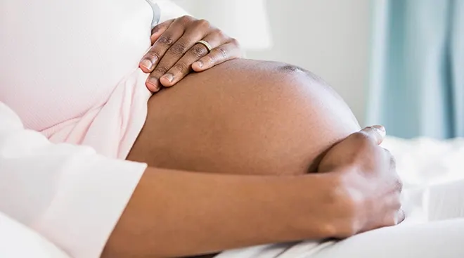 close up of pregnant woman's belly sitting on couch at home