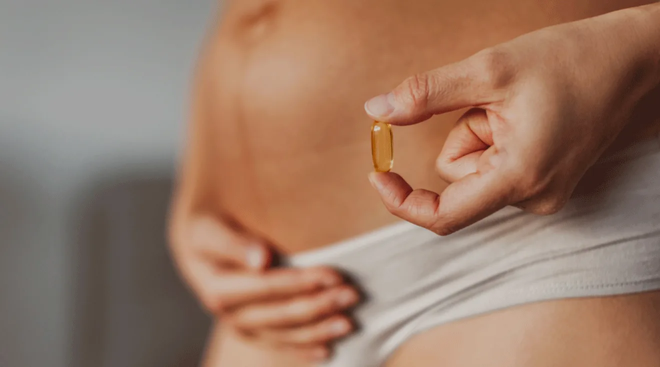 pregnant woman holding a prenatal vitamin capsule