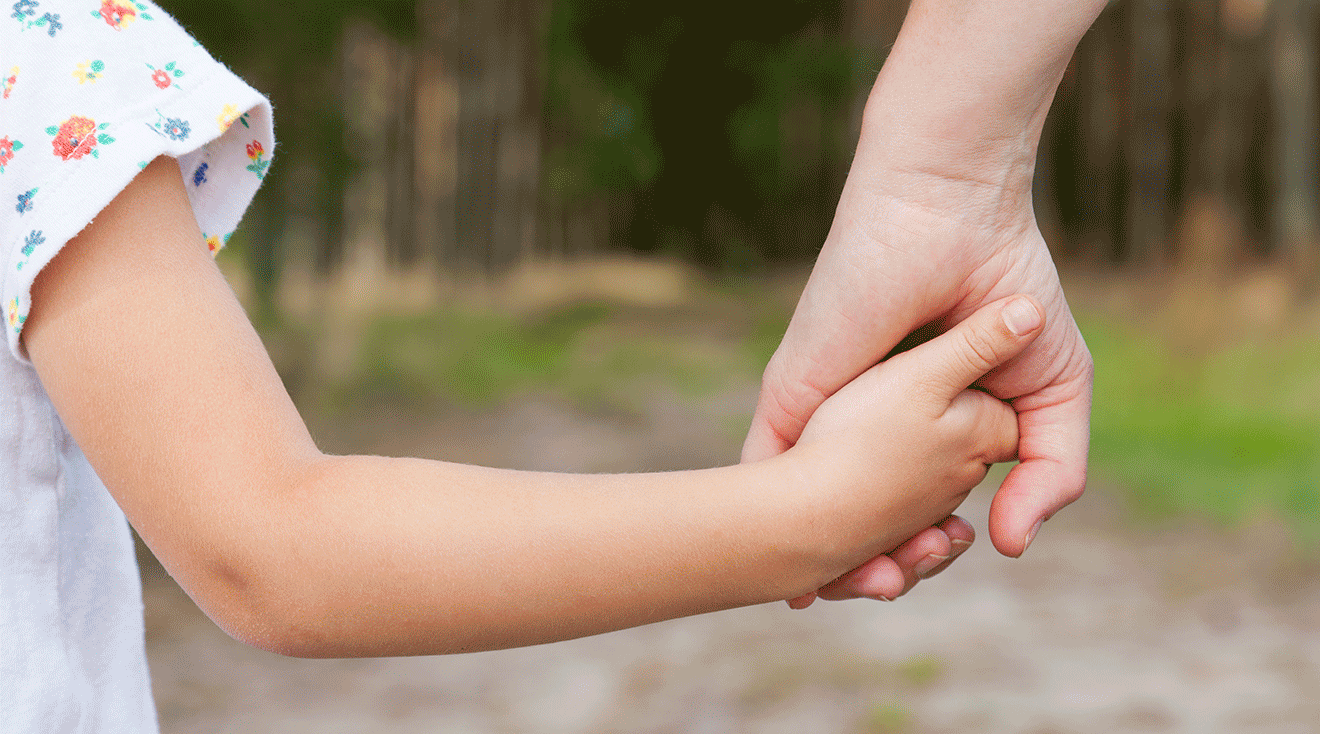 mom and child holding hands outside on summer day