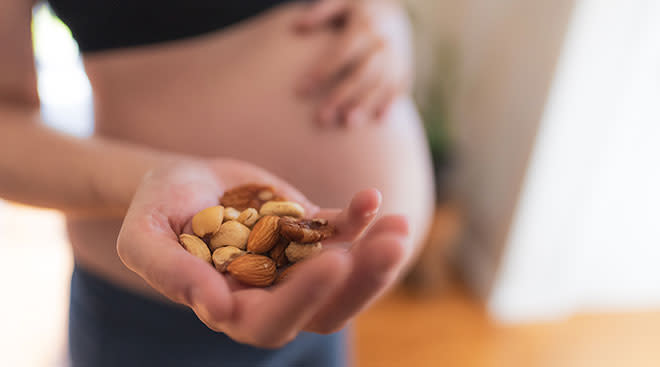 pregnant woman holding a handful of mixed nuts