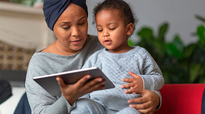 mom helps her toddler use digital tablet