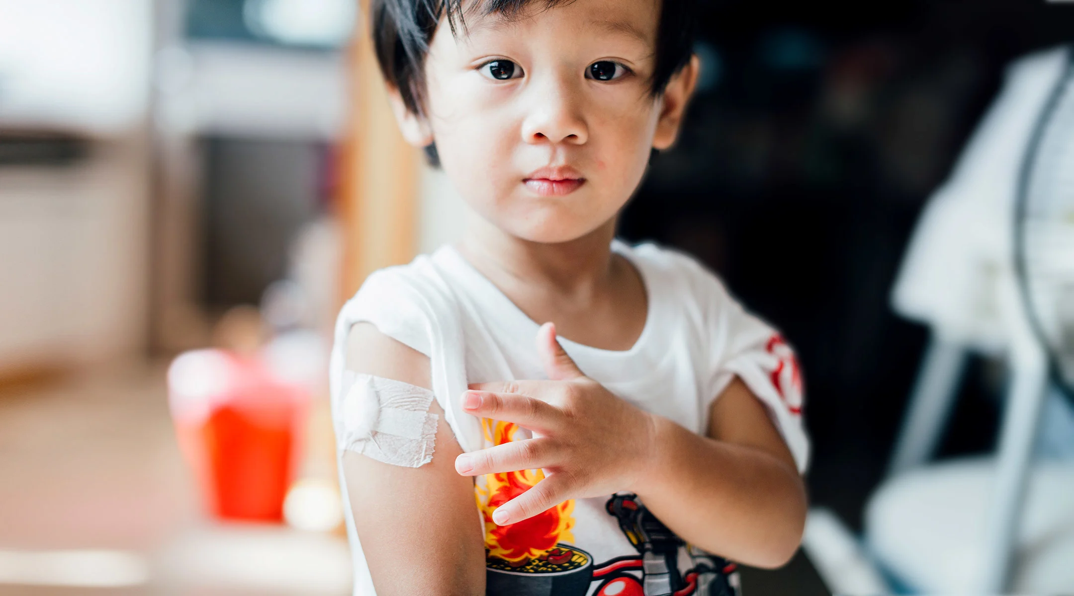 toddler boy with vaccine band aid on arm