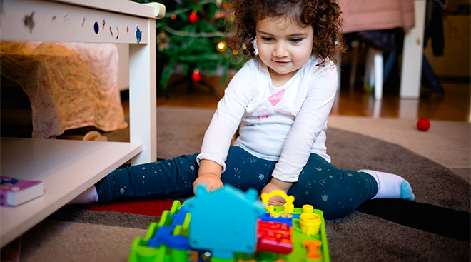 smiling toddler girl with just opened christmas toy